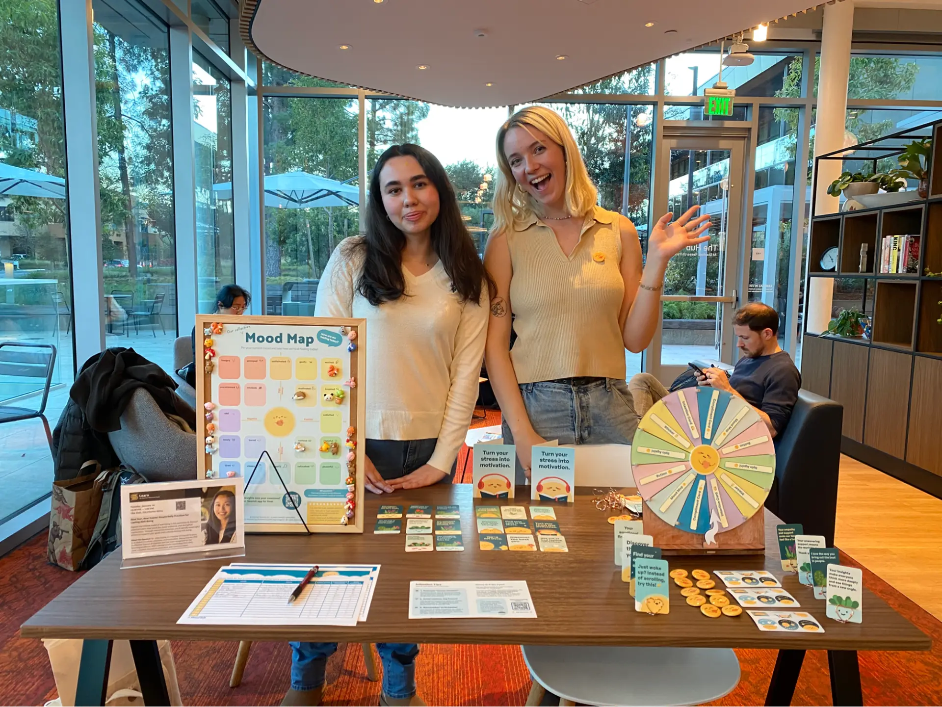 Peer wellness educators at a workshop table with the Mood Map, compliment cards, and well-being activities